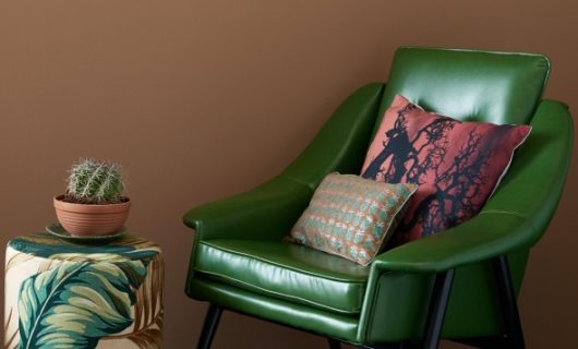 Groene vintage fauteuil van Kare-design steekt mooi af tegen de tabakbruine kleur van de wand