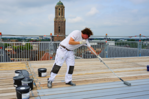 Schildersbedrijf Sale brengt de Wijzoplex Eiglans aan op het panoramadek in Zwolle. Op de achtergrond is de bekende Peperbus te zien.